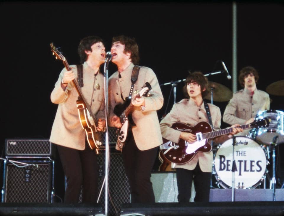The Beatles performing live at Shea Stadium in New York City on August 15, 1965. Original source: Beatles Bible, www.beatlesbible.com/1965/08/15/live-shea-stadium-new-york/.